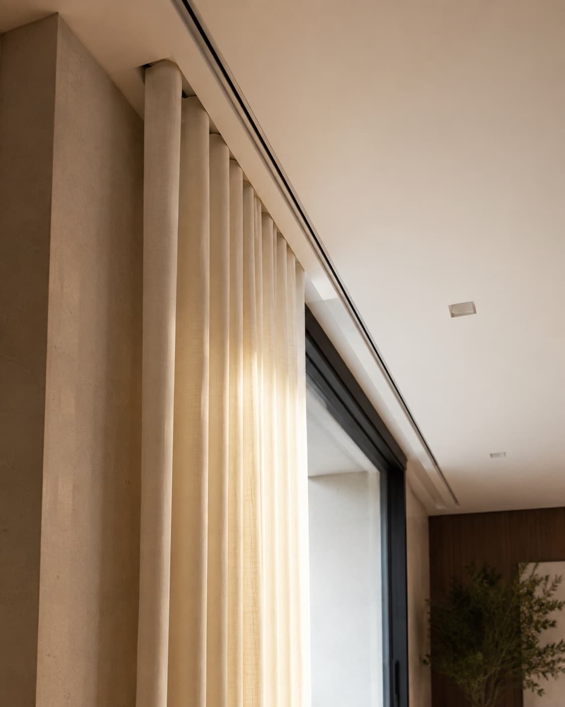 Ceiling-recessed motorised curtain track running the length of a window wall